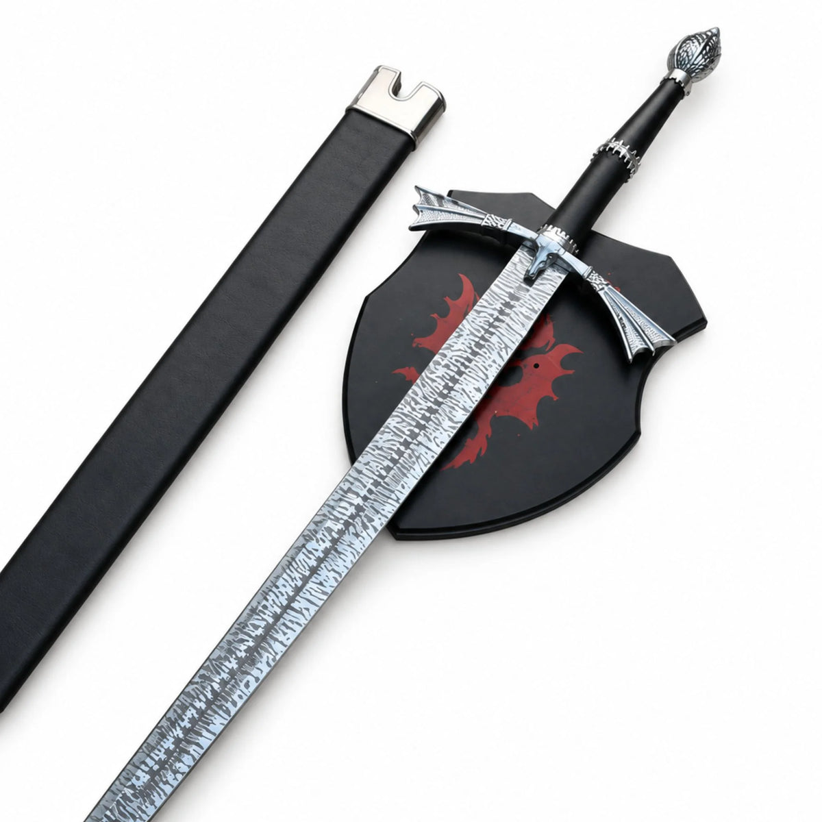 A decorative sword with a textured silver blade, black hilt, and silver pommel, displayed alongside a black sheath and a black shield featuring a red dragon emblem, on a plain white background.
